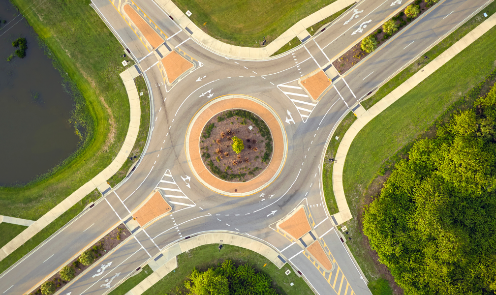 Realistic image of a roadway with green bike lane marking painted on the road next to a row of parked cars.