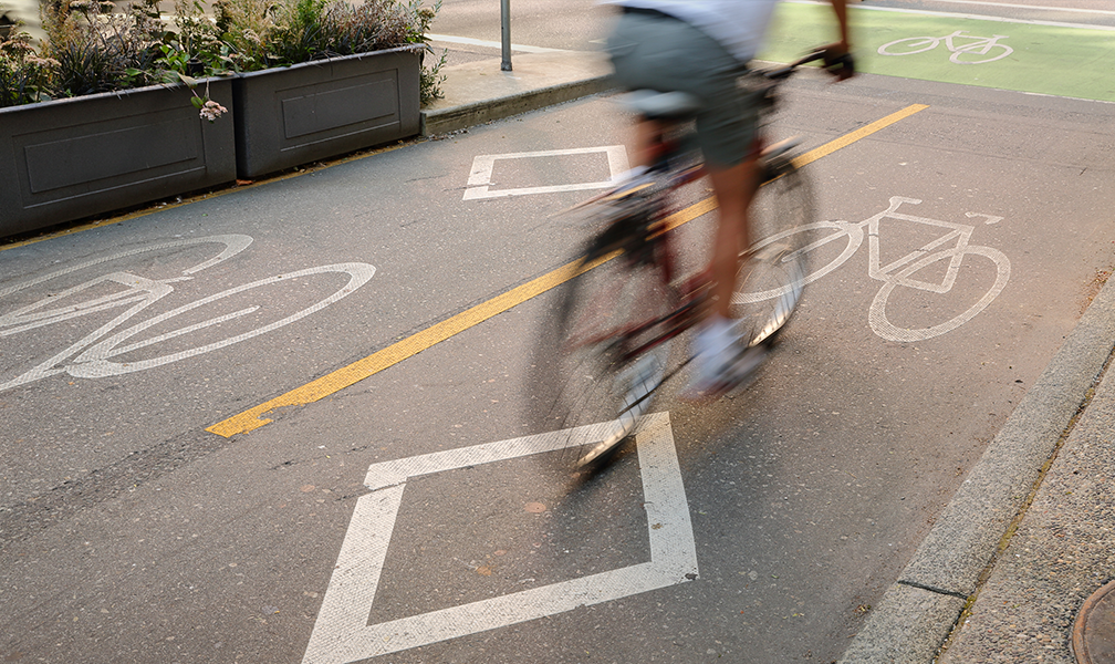 Realistic image showing an aerial view of a city roadway system with vehicles navigating turns and on-ramps.